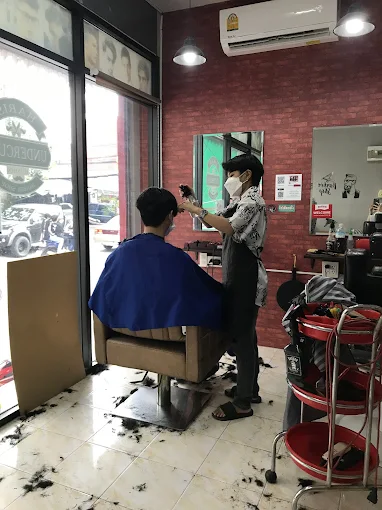 Barber working inside the shop with red brick wall